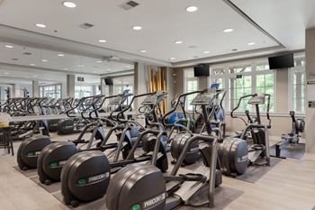 A gym with cardio equipment and weights in the lobby of a building